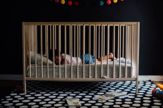 Baby Sleeps Against Side of Crib