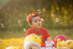 Adorable baby girl playing with toys and soap bubbles outdoors, capturing childhood innocence.