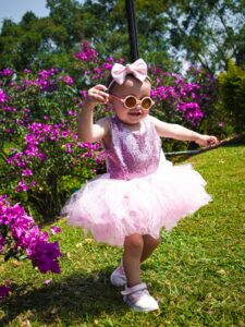 Cute child in a pink dress enjoying a sunny day in a garden in Colombia.