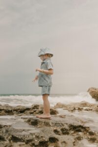 Young child exploring rocky shoreline at Tequesta beach in Florida. Perfect for family vacation themes.